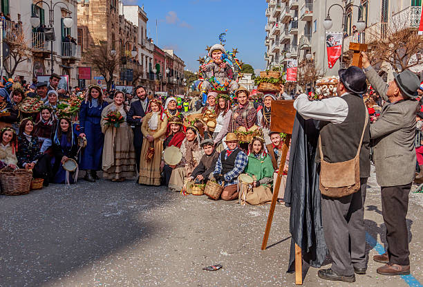 Putignano Carnival: allegorical scene representing peasant life of the past.ITALY Putignano,Apulia,Italy - February 15, 2015: carnival masks representing Italian peasant population of the past; it is a scene of a group photo of a farmer wedding .In the background float allegorical representative Angela Merkel while she torture the Europe Union . painted masquerade masks stock pictures, royalty-free photos & images