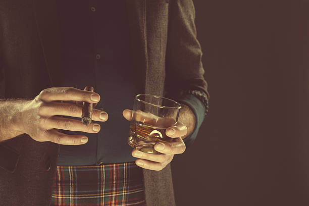 istock Man drinking whiskey and smoking cigar, close up of hands 508419174