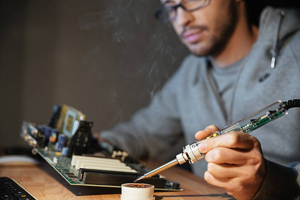 istock Thoughtful man using soldering iron for repairing motheboard 508419976