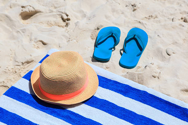 istock Straw hat, towel and flip flops on a sand beach 508420511