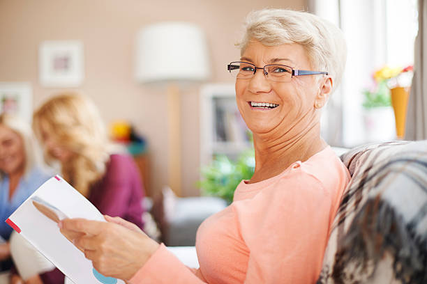 ポートレート笑顔の老人女性の読書新聞 - grandparent senior adult child reading ストックフォトと画像