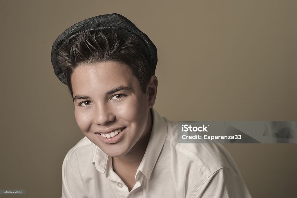 Laughing boy with a cap on a brown background 12-13 Years Stock Photo