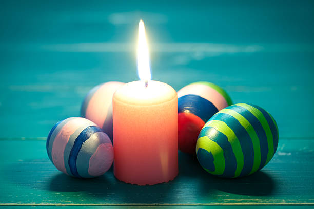 Colorful easter eggs and candle on turquoise wooden table. This file is cleaned and retouched.