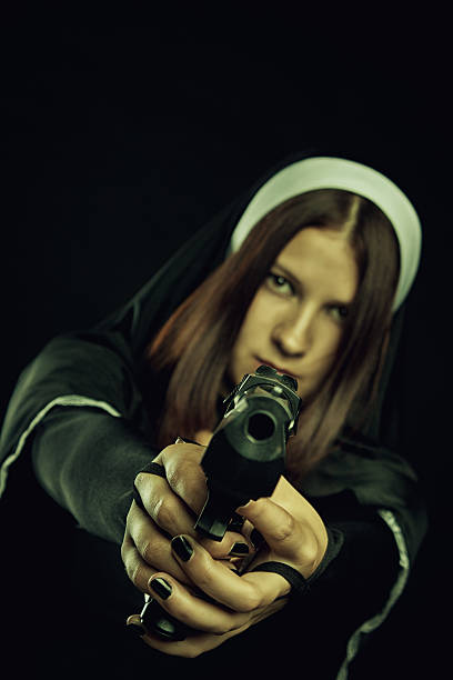 Nun with gun Pretty nun aiming with gun. Focus on hands. angry nun stock pictures, royalty-free photos & images
