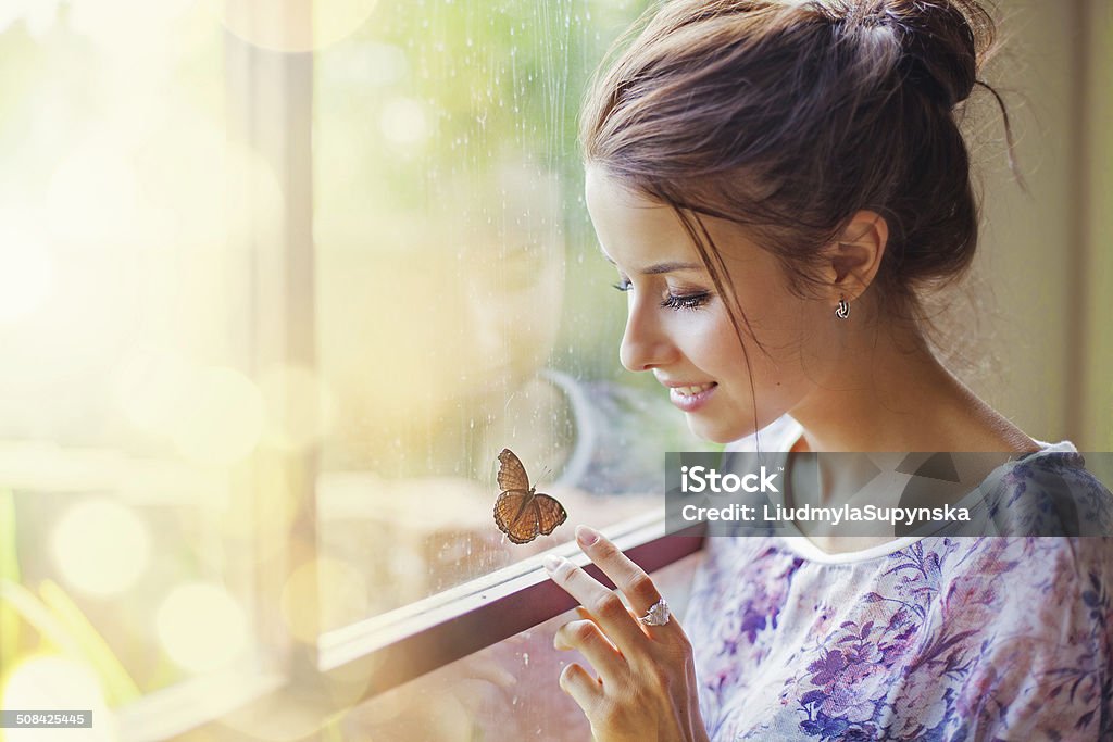 Beautiful woman with butterfly Women looks at butterfly near the window Women Stock Photo