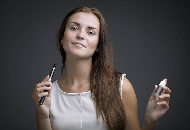 istock Woman holding e-cigarette and bottle of liquid 508426783