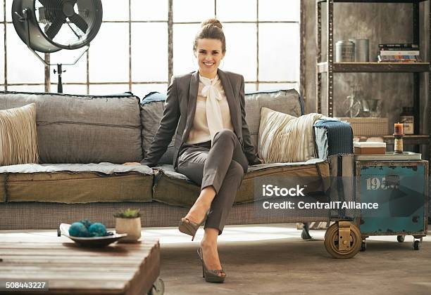 Happy Business Woman Sitting In Loft Apartment On Couch Stock Photo - Download Image Now