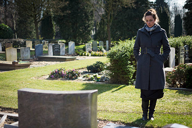 Woman standing at grave stock photo