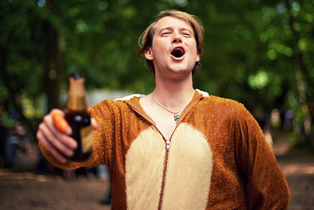 Behold the party animal Shot of a young man drinking outside while dressed in a bear suit drunk stock pictures, royalty-free photos & images