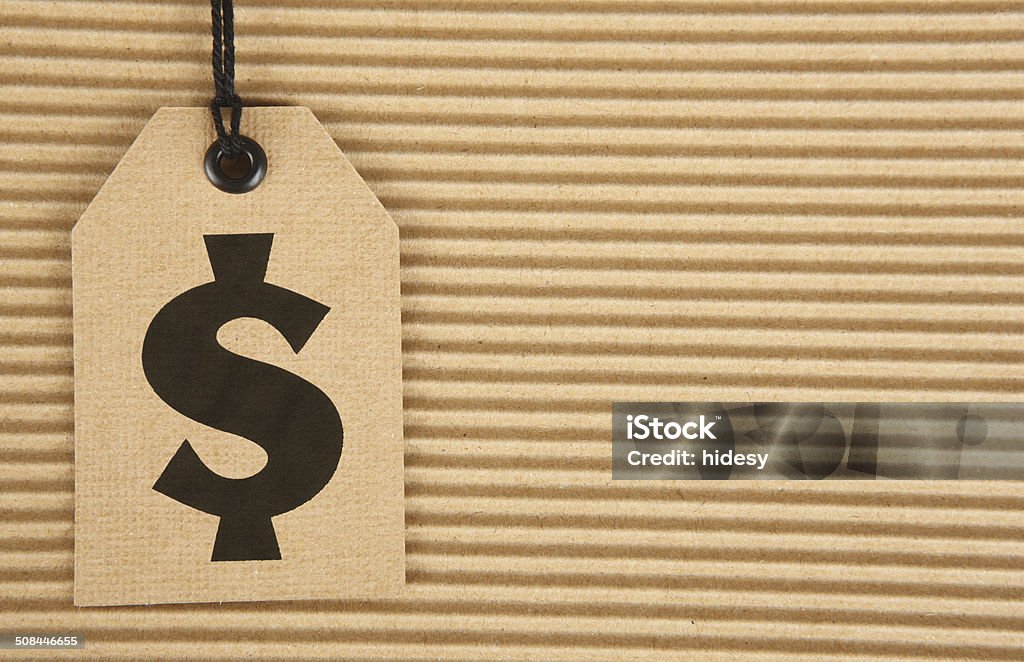 Dollar Sign on Cardboard Tag on Corrugated Cardboard Dollar Sign (designed by me) on cardboard tag on corrugated cardboard background. Brown Stock Photo