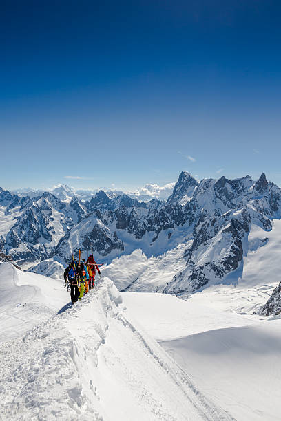 Alpine climbers on ridge at Mont Blanc, Chamonix, France DSLR picture of Alpine climbers going down the ridge at l'Aiguille du Midi to reach the Mont Blanc summit. The climbers are on the foreground and the alps are in the background and the sky is clear. aiguille de midi photos stock pictures, royalty-free photos & images