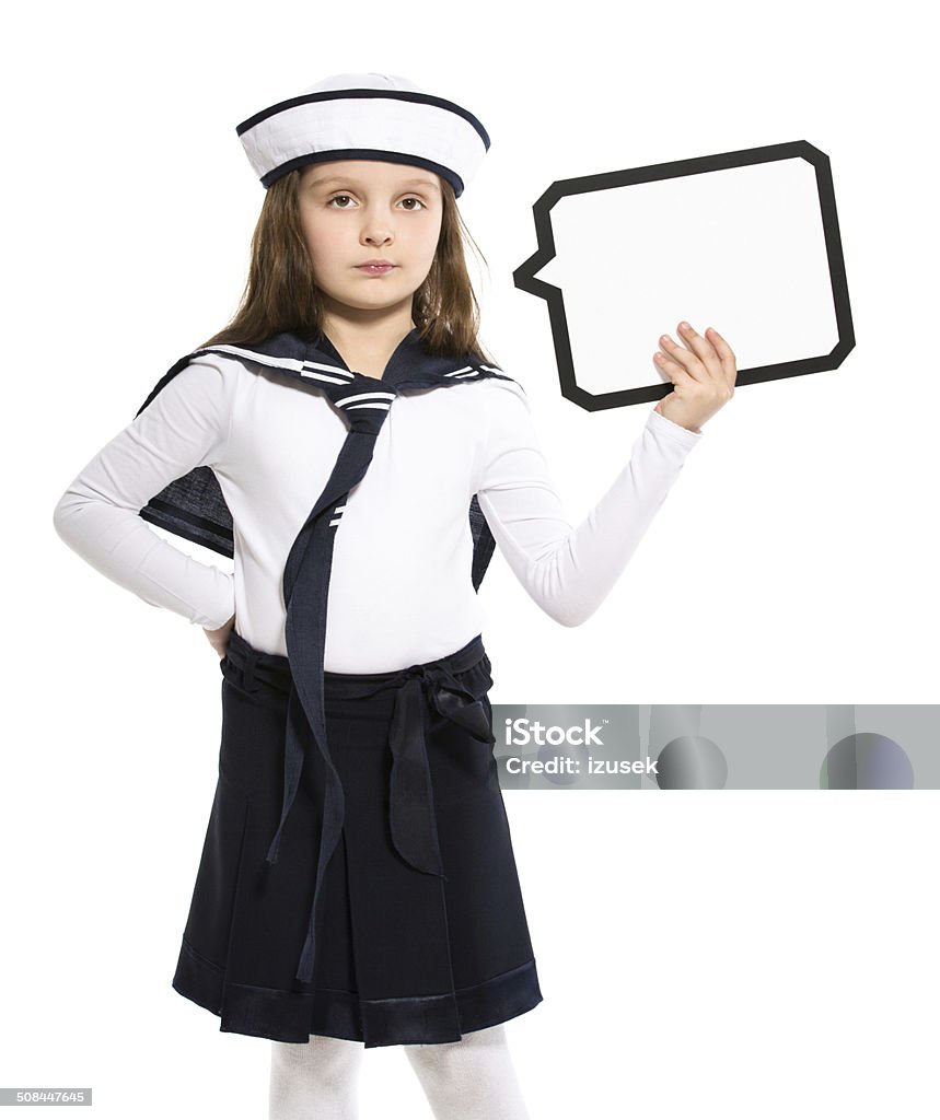 Sailor Girl with Speech Bubble Portrait of little girl dressed as a sailor holding speech bubble next to her head. Studio shot, isolated on white. 6-7 Years Stock Photo