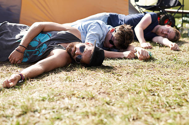 They've had one too many... Shot of two young men lying on the grass after drinking too much at an outdoor festival drunk stock pictures, royalty-free photos & images