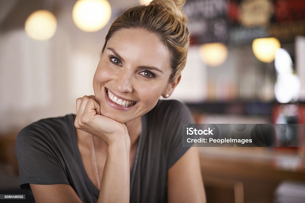 Happiness personified A cropped portrait of a beautiful young woman sitting in a coffee shop Customer Stock Photo