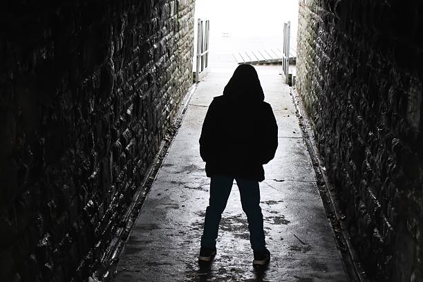 Aggressive underpass Hooded boy silhouetted in an underground tunnel silhouette of bad boy stock pictures, royalty-free photos & images