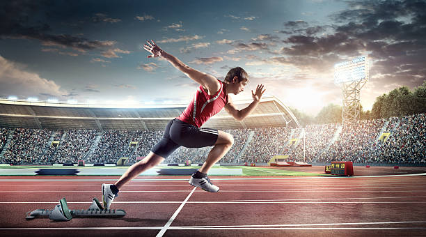 Male athlete sprinting Professional male athlete sprinting from blocks on numbered start line on outdoor athletics track on . stadium full of spectators under a sunny and cloudy sky. Sprinter is wearing generic athletics kit. sprint stock pictures, royalty-free photos & images