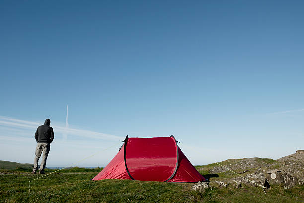 istock Camping, Man with red tent on the Cornish Coast 508455466