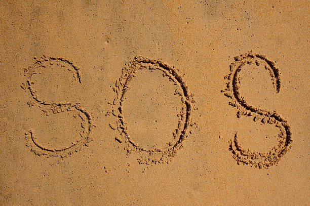 istock S.O.S written the sand with a finger or stick 508455648
