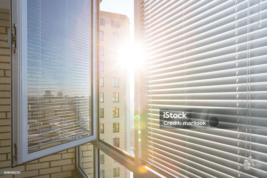 Horizontal plastic jalousie under sun rays Opened window on sunny day with horizontal plastic blinds Window Blinds Stock Photo
