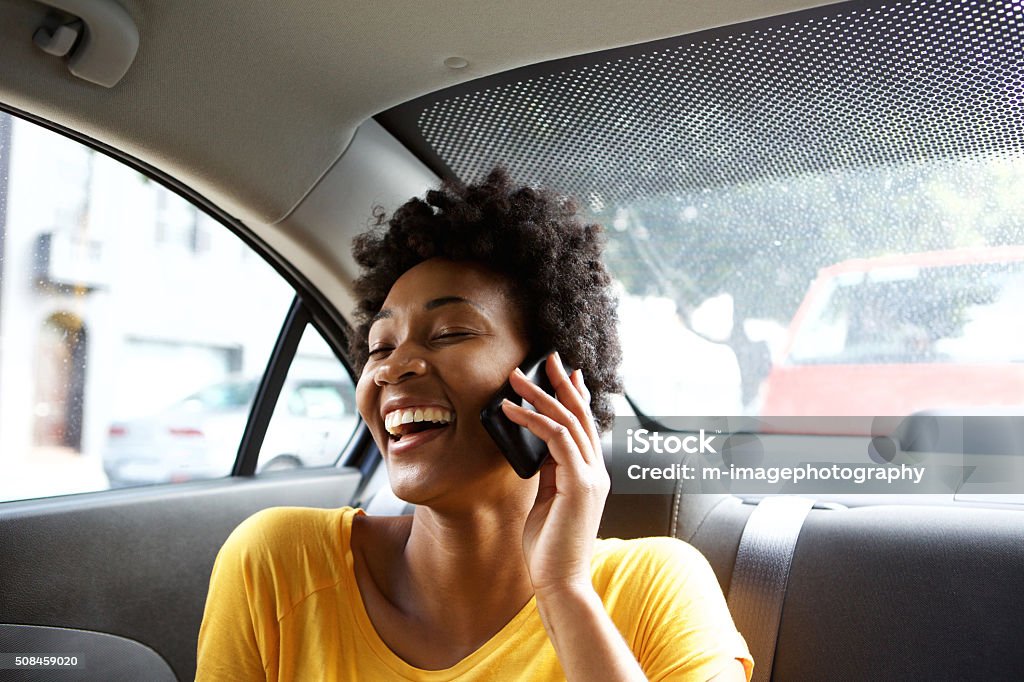 Mujer joven sonriente en un coche hablando por teléfono móvil - Foto de stock de Coche libre de derechos