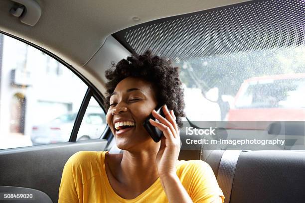 Mujer Joven Sonriente En Un Coche Hablando Por Teléfono Móvil Foto de stock y más banco de imágenes de Coche