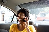 Laughing young woman in a car talking on mobile phone