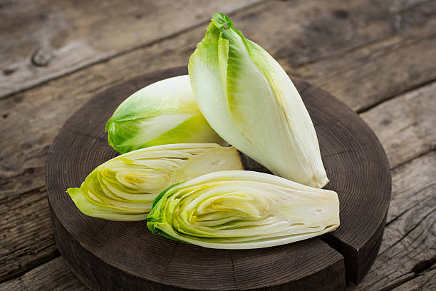 fresca witloof en la mesa de madera - chicory fotografías e imágenes de stock