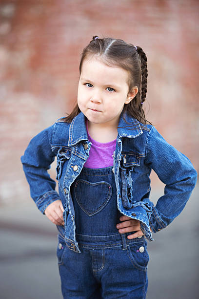 очаровательная маленькая девочка с руки на бедра злой - anger child braids braided стоковые фото и изображения
