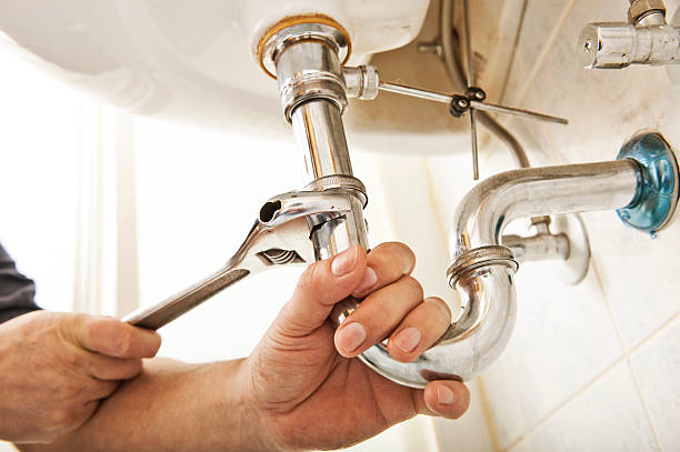 Plumber at work Plumber using a wrench to tighten a siphon under a sink plumbing fixture stock pictures, royalty-free photos & images