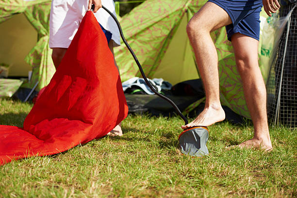 Camping time!!! Cropped shot of two people blowing up an inflatable mattress with a pump music festival camping summer vacations stock pictures, royalty-free photos & images