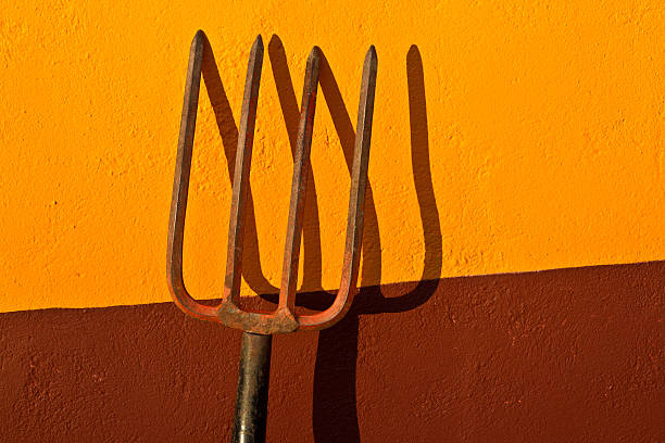 Santa Fe Style: Garden Pitchfork at Golden Hour Santa Fe style: a garden pitchfork against a painted adobe wall at golden hour. antique pitchfork stock pictures, royalty-free photos & images
