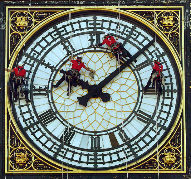 At the Clock Face London, UK - August 21st 2014:Workers cleaning  as they abseil across the clock face of Big Ben at the Houses of Parliament in Westminster big ben stock pictures, royalty-free photos & images