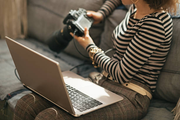 istock Closeup on woman with laptop using modern dslr photo camera 508471463