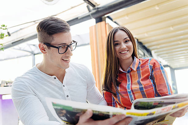 istock Young couple reading newspaper and drinking coffee in modern cafe 508488644