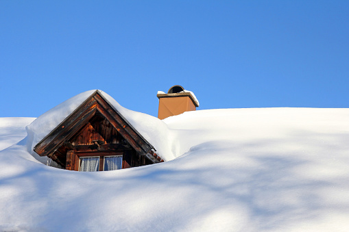 A snowed roof window of an old wooden house