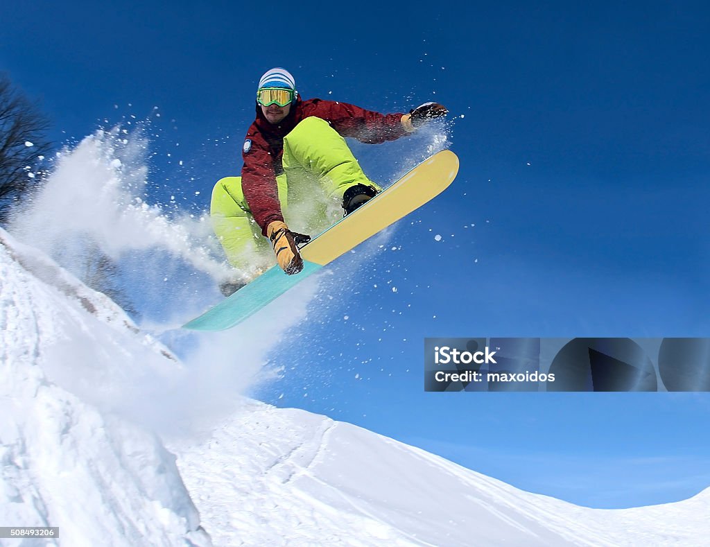 Snowboarder in the sky Jumping snowboarder keeps one hand on the snowboard on blue sky background Snowboarding Stock Photo