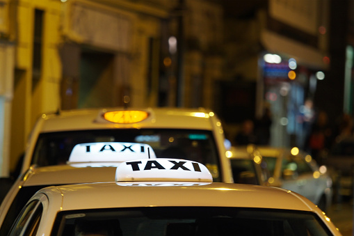 A row of taxis wait for custom in a British city centre at night