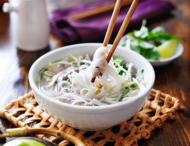 picking up noodles out of a bowl of pho picking up noodles out of a bowl of pho with chopsticks. Shot with selective focus vietnamese culture stock pictures, royalty-free photos & images