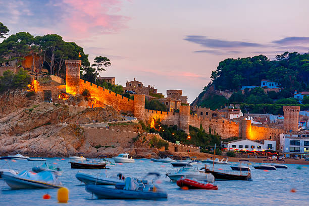 Tossa de Mar on the Costa Brava, Catalunya, Spain Fortress and fishing boats at Gran Platja beach and Badia de Tossa bay at sunset in Tossa de Mar on Costa Brava, Catalunya, Spain tossa de mar stock pictures, royalty-free photos & images