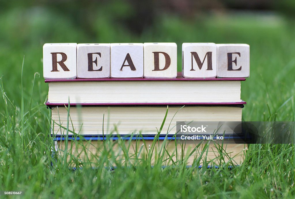 Read me text on the book stack Book stack on teh grass with "ream me" text on the top. Good suggestion for studens and pupils. Paperback Stock Photo