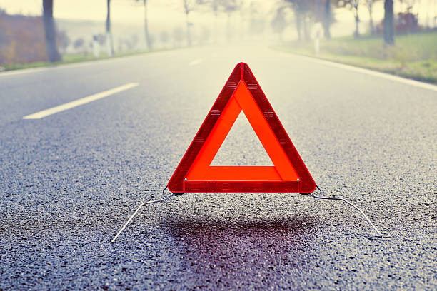 schlechtes wetter driving-warnung dreieck auf einen nebligen road - road warning sign stock-fotos und bilder