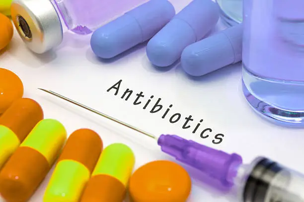 Antibiotics - diagnosis written on a white piece of paper. Syringe and vaccine with drugs.