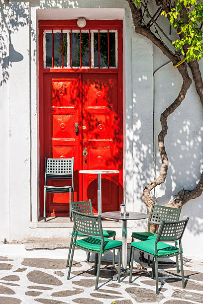 Street cafe terrace in front of a red door, Mykonos stock photo