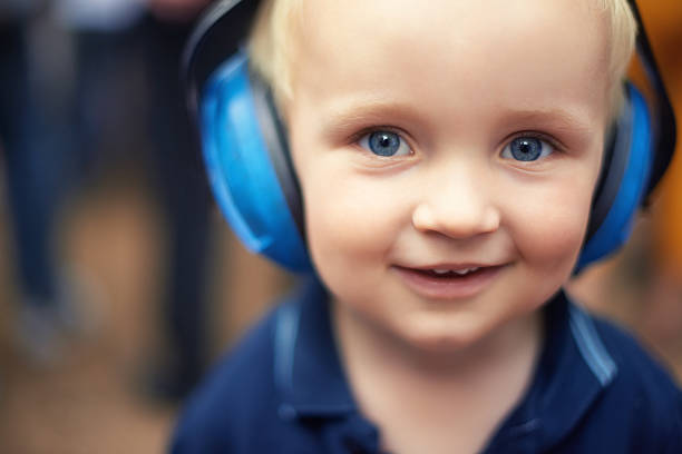 Pure bliss Shot of a little boy wearing ear protectors at an outdoor music festival little boys blue eyes blond hair one person stock pictures, royalty-free photos & images