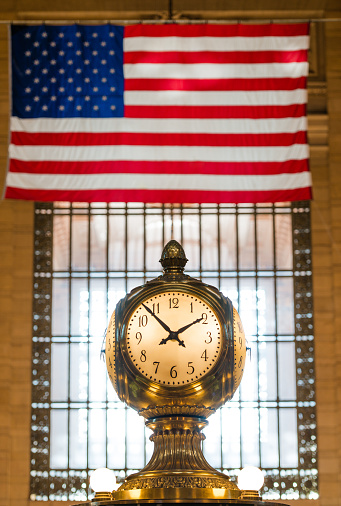 New York, USA - January 13, 2016: An HDR image of an American flag and clock at Grand Central Station at 1:54 pm. 