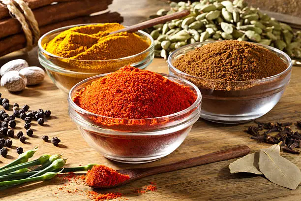 Photo of Three bowls filled with spices on rustic wood table