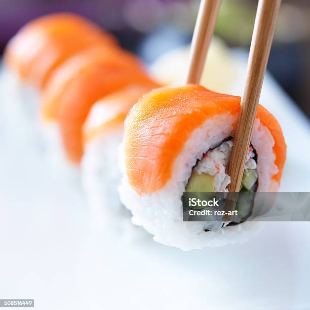 Picking Up A Piece Of Sushi With Chopsticks Stock Photo - Download Image Now - Sushi, Avocado, Rolled Up