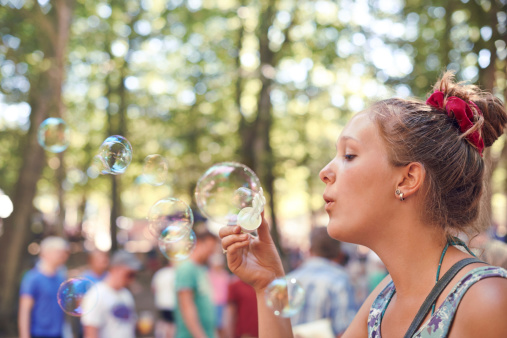 Shot of an attractive young woman blowing bubbles at an outdoor festival