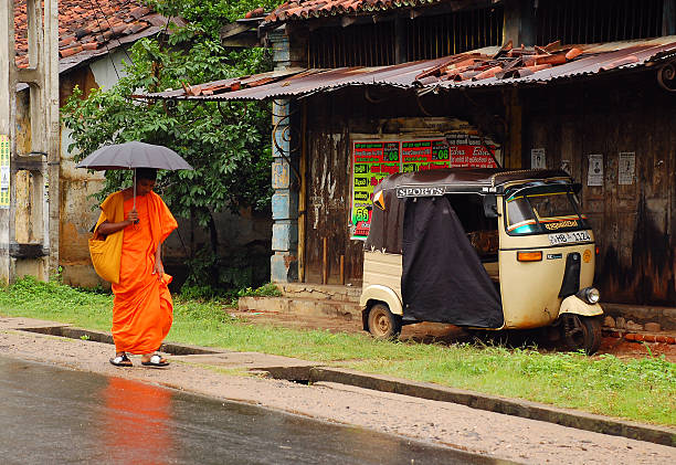 Monk in The Street Kandy, Sri Lanka - December 6, 2008: Young monk walks down the street to the temple in the rain holding umbrella down taxi sri lanka stock pictures, royalty-free photos & images