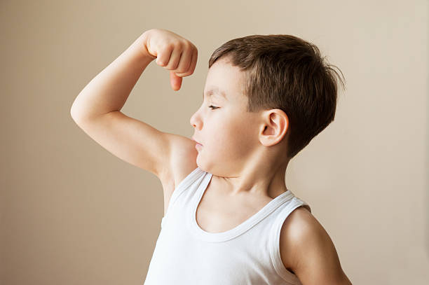 bambino ragazzo bambino mostrando i muscoli pugno l'allenamento - human muscle human arm bicep muscular build foto e immagini stock